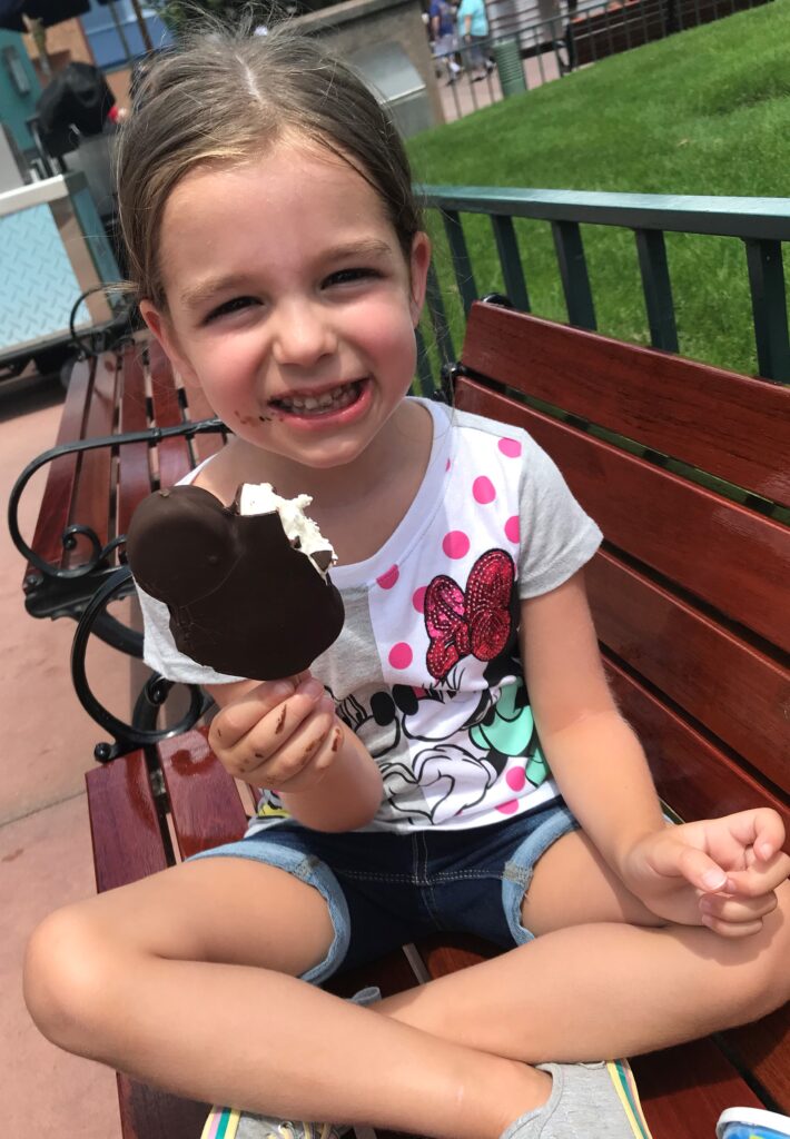 Girl enjoying Mickey Ice Cream Bar at Disney