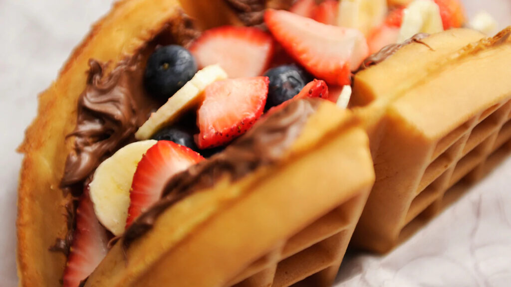 Nutella y sándwich de gofres de fruta fresca con fresas, plátanos y arándanos