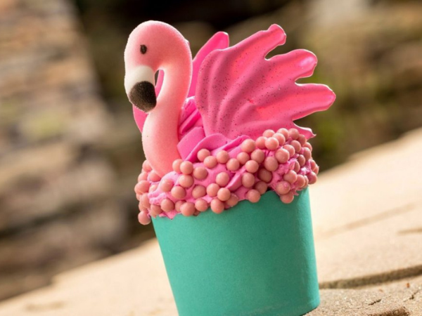 A cupcake topped with frosting and a candy flamingo