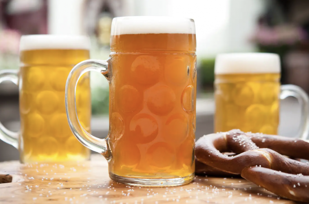 Foto de cervezas en tazas y pretzel.