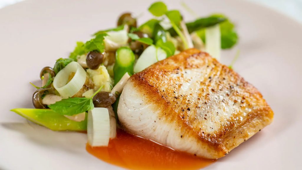 Un trozo de pescado blanco servido con ensalada de espárragos, champiñones y patatas - Citricos